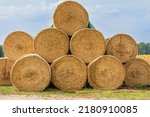 stacked hay bales after harvest at the edge of the field. dry straw pressed into individual straw bales. Pile of straw bales. Structures of hay and straw. clouds at background