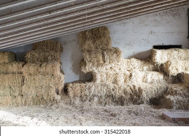 stacked hay bales in the barn of a horse stable - useful as a background - focus on the center of the image