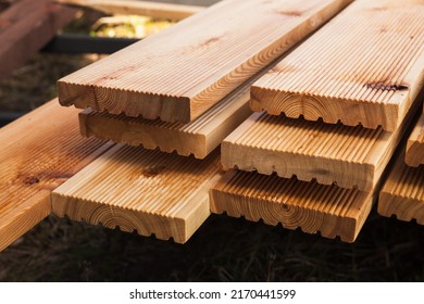 Stacked larch deck boards, close up outdoor photo with selective soft focus