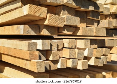Stacked lumber. Folded wood. Closeup wooden boards. The surface of the end of the board. Lots of planks stacked on top of each other in the warehouse. Lumber for use in construction.