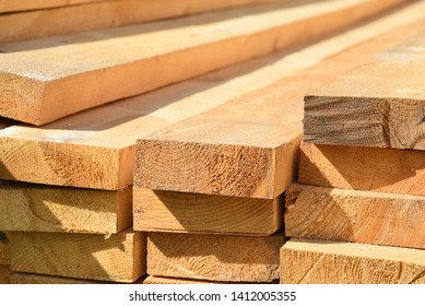 Stacked lumber. Folded wood.Closeup wooden boards.The surface of the end of the board.Lots of planks stacked on top of each other in the warehouse.Lumber for use in construction.