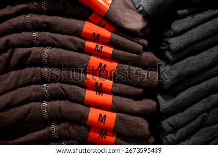Stacked medium or M-sized clothes are being sold in a department store.