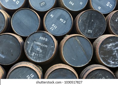 Stacked Pile Of Old Wooden Barrels And Casks At Whisky Distillery In Scotland.