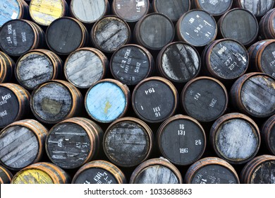 Stacked pile of old wooden barrels and casks at whisky distillery in Scotland.