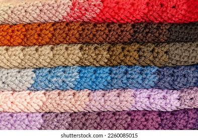 Stacked rainbow  colored  crocheted garment items 