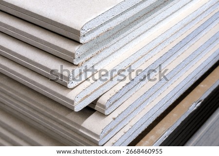Stacked sheets of engineered sheets of plasterboard material at a construction site ready for use in furniture and interior design projects