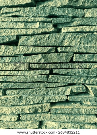 Stacked slate stone wall with teal-green cross-processed toning. Detailed horizontal stone texture ideal for moody backgrounds, editorial layouts, and architectural surfaces.