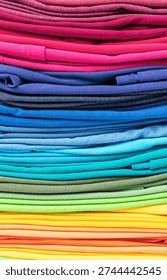 Stacked stack of multi-colored T-shirts in the form of texture or background, vertical orientation