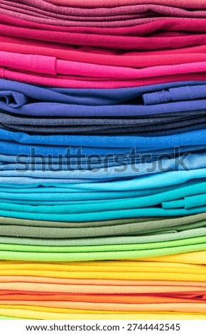 Stacked stack of multi-colored T-shirts in the form of texture or background, vertical orientation