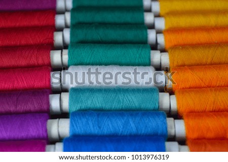 stacked thread rolls of different colors with some parts in focus