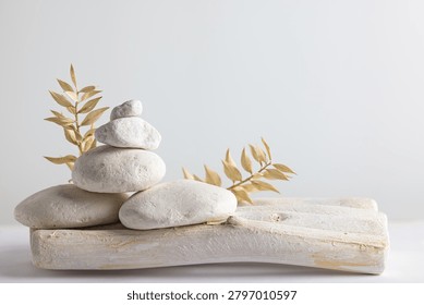 Stacked white pebbles on rustic wooden tray with dried leaves for spa wellness balance and minimalist decor