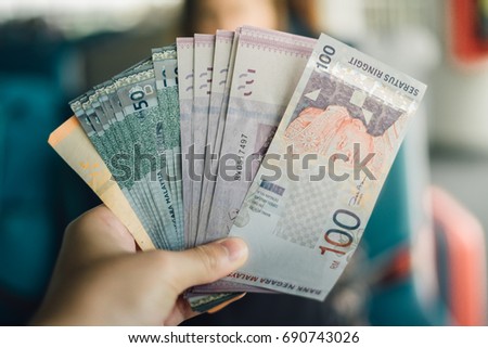 Stacking Ringgit Malaysia bank note on hand.