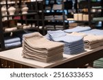 Stacks of beige and blue towels displayed on a table in a store. Home textile retail interior