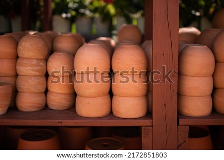 Stacks of ceramic red clay brick pots for plants in a greenhouse conservatory plant shop setting. Groups of traditional earthenware rustic flowerpot containers in a plant shop market.