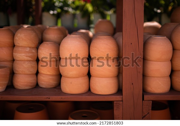 Stacks of ceramic red clay brick pots for plants\
in a greenhouse conservatory plant shop setting. Groups of\
traditional earthenware rustic flowerpot containers in a plant shop\
market.