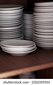 Stacks Of Clean White Plates On Shelf. Close Up