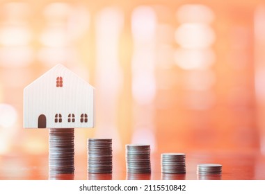 Stacks Of Coins On Desk With Mockup Wooden Houses; Investments; Business Growth; Saving Money; Transactions; Taxes; Building A House; Borrowing Money; Bank Deposits; Financial Management; Target.
