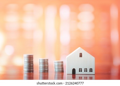 Stacks Of Coins On Desk With Mockup Wooden Houses; Investments; Business Growth; Saving Money; Transactions; Taxes; Building A House; Borrowing Money; Bank Deposits; Financial Management; Target.
