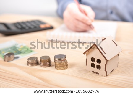 Stacks coins on wooden table with calculator. man using calculator calculating monthly home expenses, taxes, bank account balance payment, concept saving money. account banking business finance
