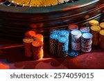 Stacks of colorful poker chips under ambient lighting create an atmosphere of anticipation and luck at the casino table.