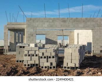 Stacks of concrete blocks in front of concrete shell of a single-family house under construction in a suburban development on a sunny morning in southwest Florida - Shutterstock ID 2249400421