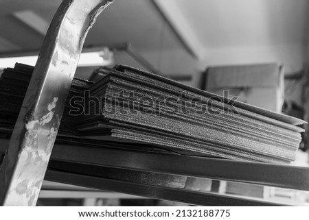 stacks of containerboard sheets in warehouse facility, monochrome