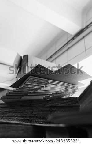stacks of containerboard sheets in warehouse facility, monochrome