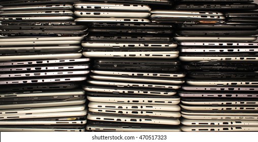 Stacks of disassembled tablets and smartphones. Plastic cases with boards and connectors. Electronics waste concept background.