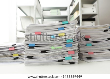 Stacks of documents with paper clips on office desk