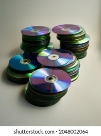 Stacks of DVDs, empty and recorded, on a white table. Copy space and selective focus.