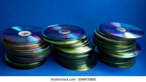 Stacks of DVDs, empty and recorded, on a blue background. Copy space and selective focus.