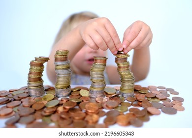 Stacks Of Euro Currency Coins, Small Child, Blonde Girl 3 Years Old Playing With Cash, Pocket Money Against White Background, Concept Of Financial Literacy Of Children, Inflation, Personal Savings