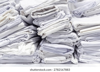 Stacks of folded white fabric on a smooth table organized piles clean textile storage preparation material handling.