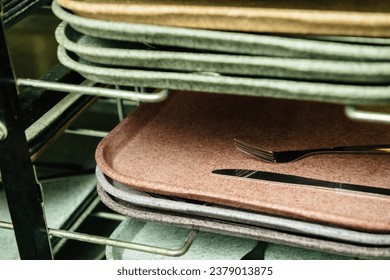 Stacks of food trays with forks and knives in a school office canteen, ready for mealtime