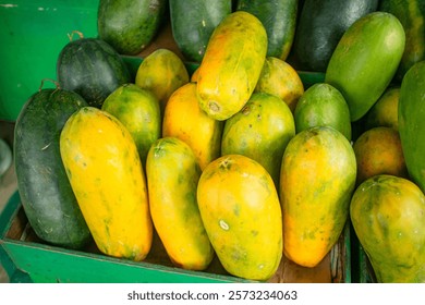 Stacks of fresh papayas and watermelons are neatly arranged at a roadside fruit shop.