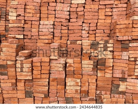 Stacks of handmade red and brown bricks neatly stacked in building materials ready to be sold. brick pile background