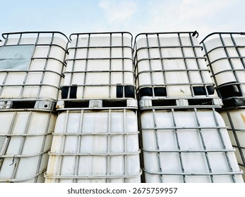 Stacks of IBCs, or Intermediate Bulk Containers. These industrial-strength containers are for the safe storage and transport of liquid and solid goods, providing an efficient and robust solution.