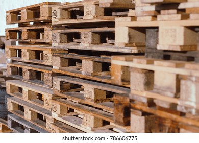 Stacks Of Old EUR Symbol Wooden Pallets In An Industrial Yard.