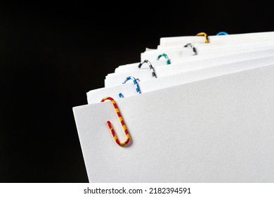 Stacks of papers with multicolored paper clips on a dark background