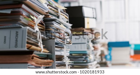 Stacks of paperwork and files in the office: work overload, files management and administration concept