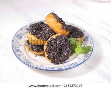 Stacks of potato dougnuts with chocholate sprinkles served in white ceramic plate. Selective focus