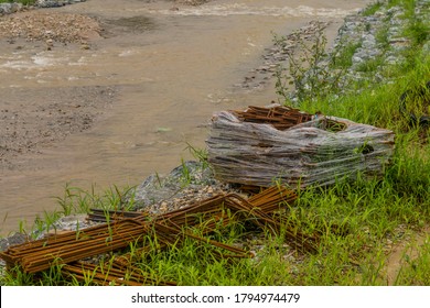 Stacks of rebar laying on shore of man made river at construction site.