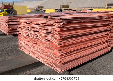 Stacks of refined copper cathodes with distinct wavy edges are prepared for dispatch at an open pit mining operation.
