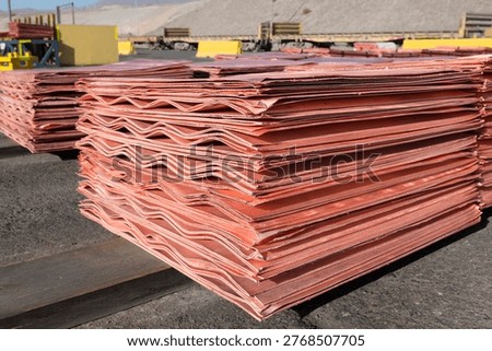 Stacks of refined copper cathodes with distinct wavy edges are prepared for dispatch at an open pit mining operation.