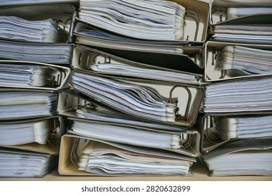 Stacks of ring binders with many documents as full frame background, business concept for excessive bureaucracy, record keeping, accounting and work overload in the office, selected focus