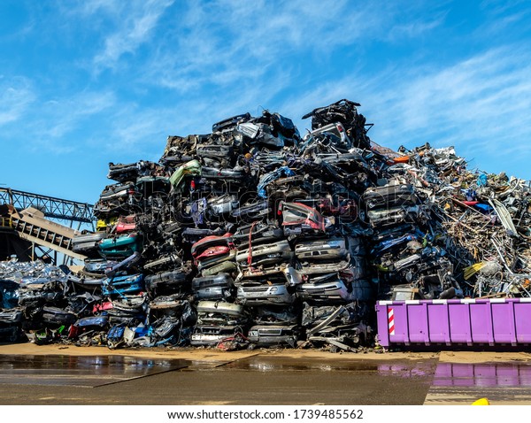 Stacks of scrapped car wrecks at a scrap yard on a\
sunny day