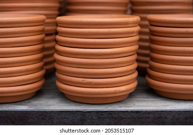 Stacks of terra cotta planter saucers are on display at a nursery and garden center.