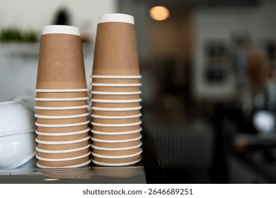 Stacks upside down empty brown takeaway disposable coffee cardboard cups on the coffee machine in the cafe