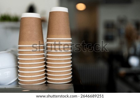 Stacks upside down empty brown takeaway disposable coffee cardboard cups on the coffee machine in the cafe