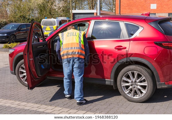Stade, Germany –\
April 16, 2021. A customs official in plainclothes wearing a\
warning vest examining a car.\
